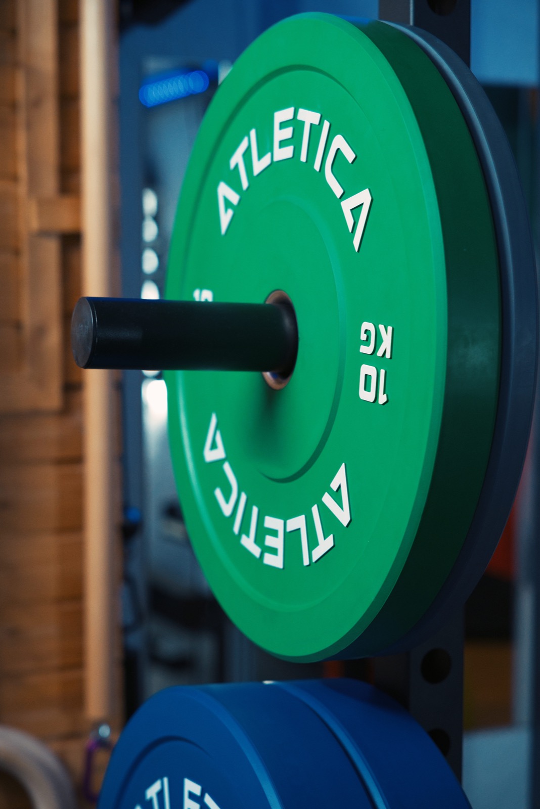 Close-up of green and blue bumper plates on the rack